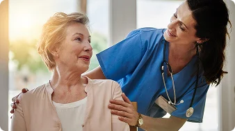 Female nurse smiling and providing compassionate care to a senior woman.