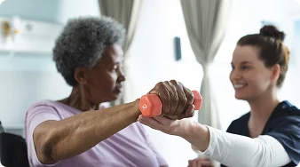 Senior woman performing arm exercises with assistance from a physical therapist.