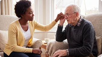 Female caregiver comforting an elderly man experiencing emotional distress at home.