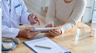 Doctor discussing medical information with a senior woman using a tablet.