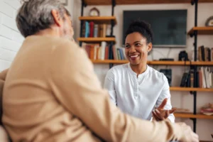 Caregiver having a friendly conversation with an elderly man at home