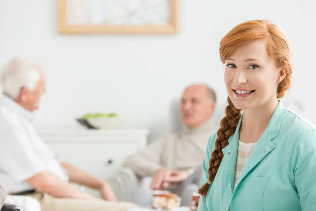 Smiling home care nurse with elderly patients in the background