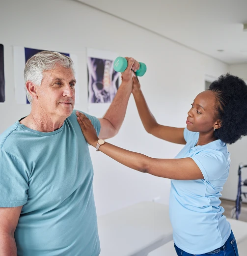 Smiling female physiotherapist helps older man with turquoise resistance band