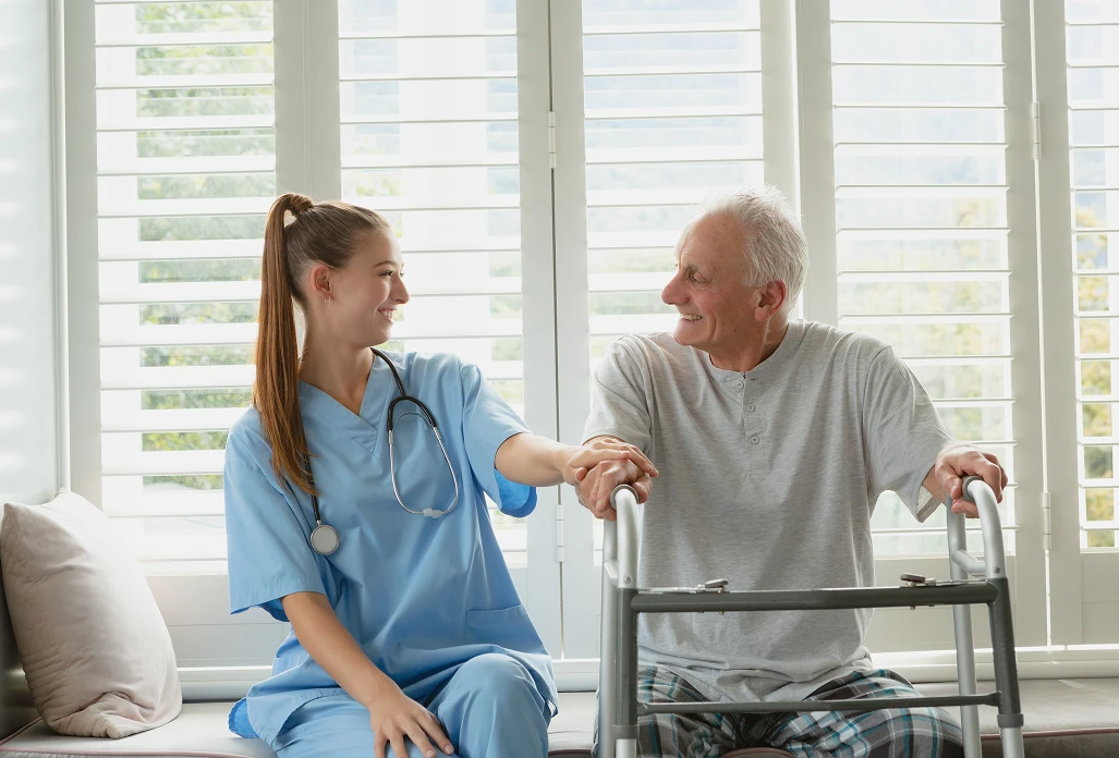 Nurse assisting elderly man with walker during rehabilitation exercise in bright home interior