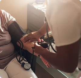 Healthcare professional measuring blood pressure of elderly patient using manual cuff during home visit