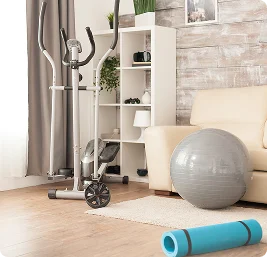 Home rehabilitation equipment including exercise bike, yoga mat, foam roller, and balance ball in living room