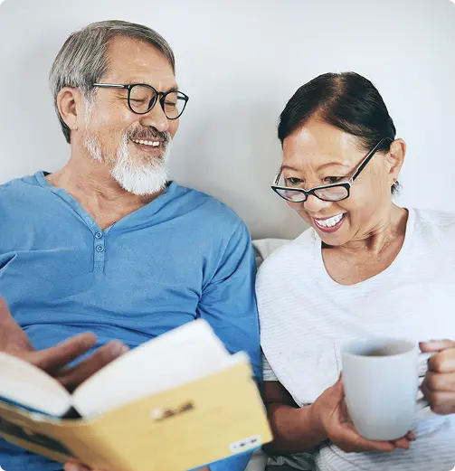Senior couple reading a book together and smiling.