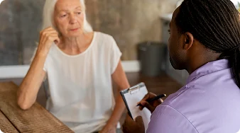 Healthcare professional discussing medical concerns with an elderly woman during a home visit.